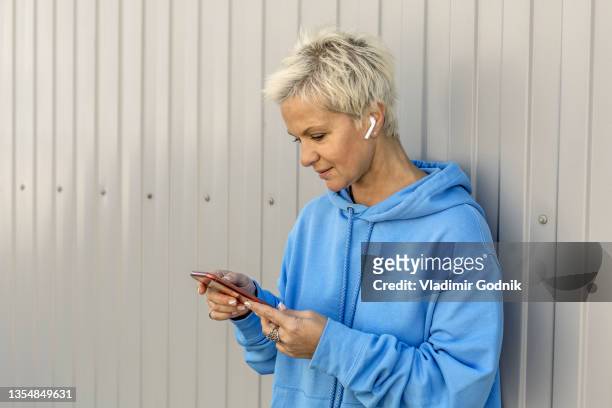 woman with earbud headphones using smart phone - hoodie headphones - fotografias e filmes do acervo