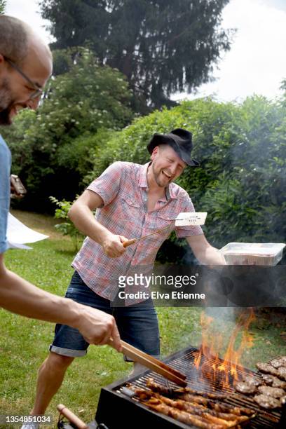 two mature men burning food on a barbecue in a back yard in summertime - burnt cooking stock pictures, royalty-free photos & images