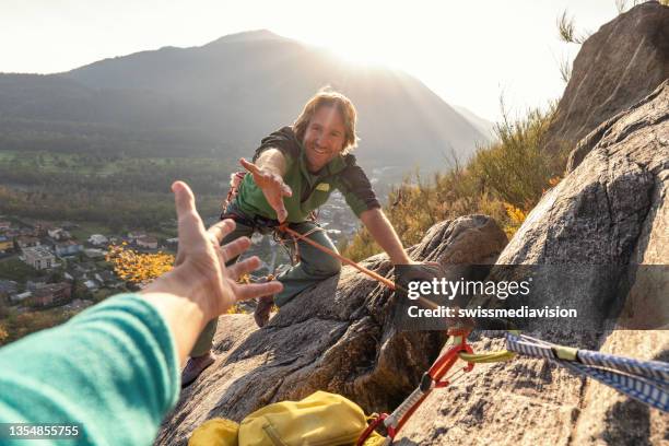 male rock climber reaches his hand out to ask for assistance - rock climbing stock pictures, royalty-free photos & images