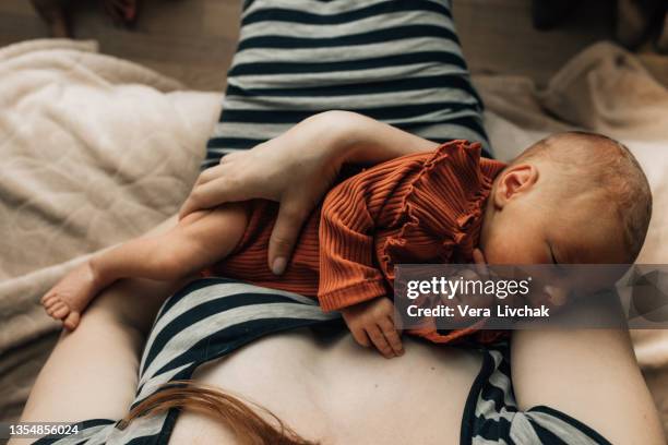 close-up of a mother holding a newborn baby at home. - écran géant photos et images de collection