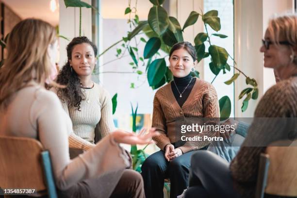 woman sharing her experiences during a group therapy session - only women stock pictures, royalty-free photos & images