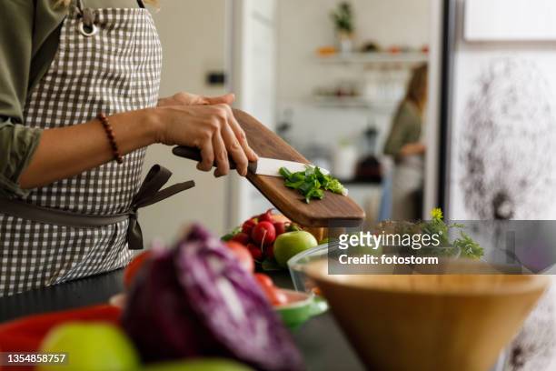 woman putting a spring onion she chopped in a glass baking tray - plant based diet stock pictures, royalty-free photos & images