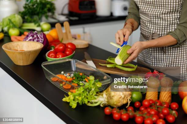 midsection of woman peeling a zucchini for a healthy dish she is preparing - peeler stock pictures, royalty-free photos & images