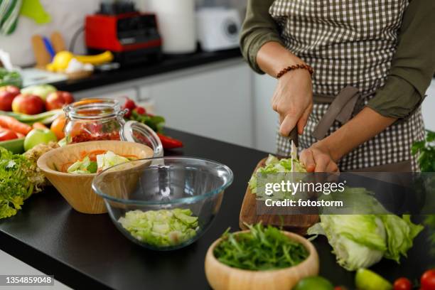 midsection of woman finely chopping iceberg lettuce for a salad she is preparing - iceberg lettuce stock pictures, royalty-free photos & images