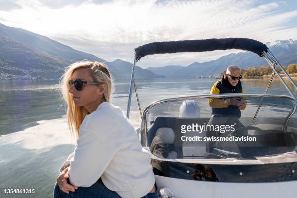 young woman and mature man on luxury boat, they enjoy the lake in autumn - early retirement stockfoto's en -beelden