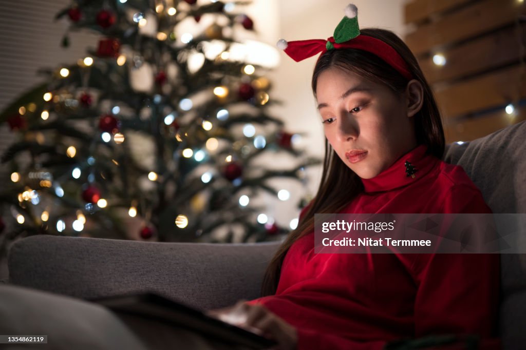 An Asian woman who spent Christmas or New year alone away while using a digital tablet at her apartment.