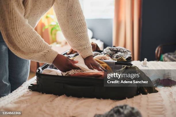 foto recortada de una mujer irreconocible empacando sus cosas en una maleta en casa antes de viajar - bagage fotografías e imágenes de stock