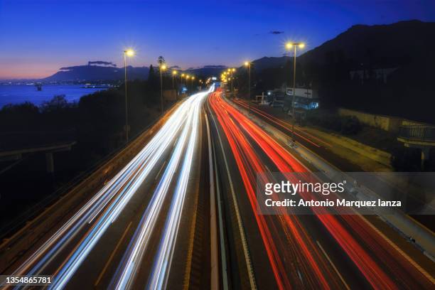 car light trails in a busy motorway on a sunset - tail light 個照片及圖片檔