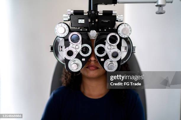 jeune femme faisant un examen de la vue dans une clinique médicale - réfracteur photos et images de collection