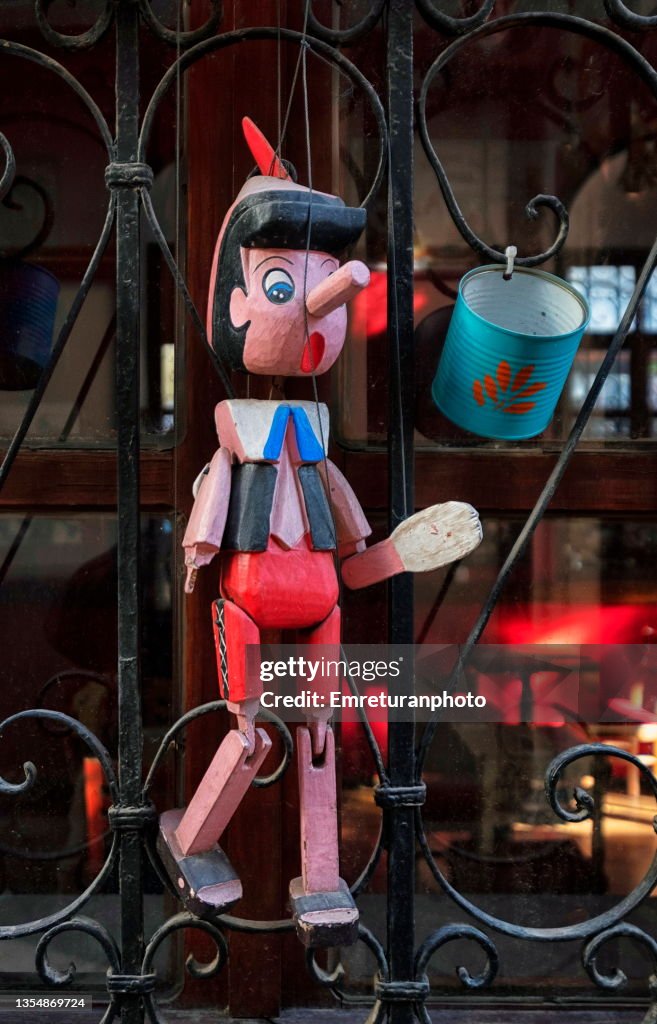 Wooden pinocchio on wrought  iron window frame.