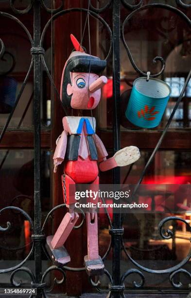wooden pinocchio on wrought iron window frame. - pinocchio stock pictures, royalty-free photos & images