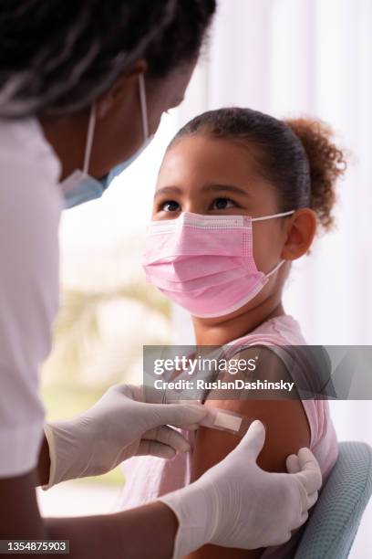 doctor putting plaster at child's hand after injection of a covid-19 vaccine. - safe injecting stock pictures, royalty-free photos & images