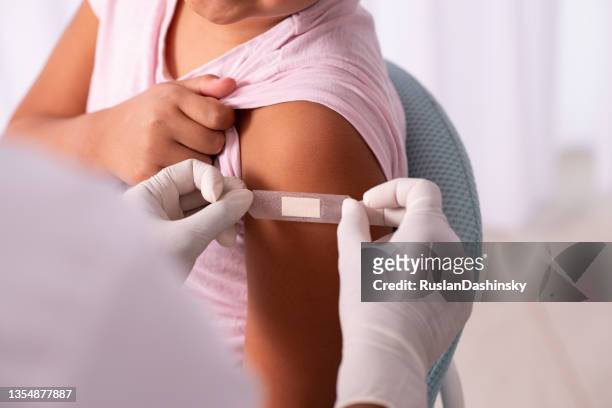 arzt, der nach der injektion eines impfstoffs gips an die hand des kindes legt. - infected wound stock-fotos und bilder