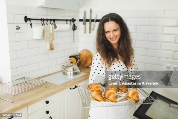 woman baking croissants in oven at home. - tin foil costume - fotografias e filmes do acervo