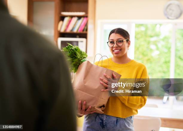 shot of a young woman carrying a bag of groceries - young man groceries kitchen stock pictures, royalty-free photos & images