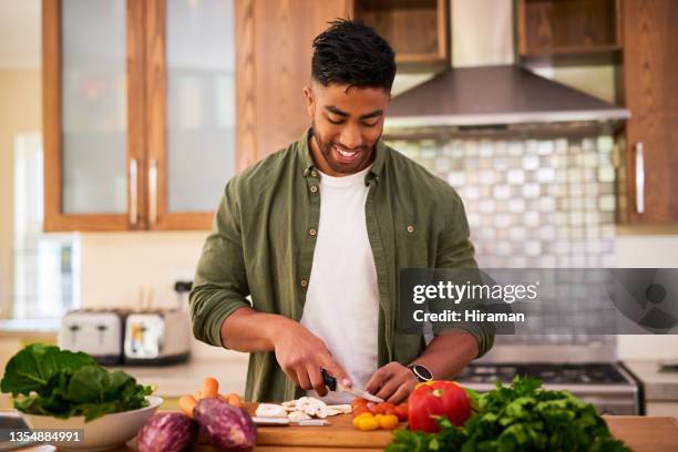 shot of a young man preparing vegetables to cook a meal - paleo imagens e fotografias de stock