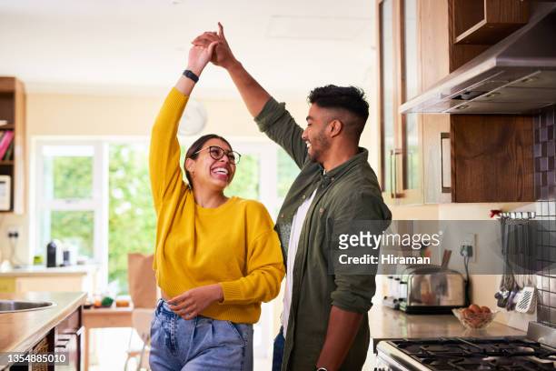 shot of a young couple dancing together in their kitchen - huis interieur stockfoto's en -beelden
