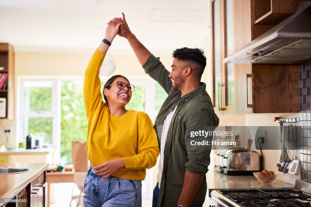 Shot of a young couple dancing together in their kitchen
