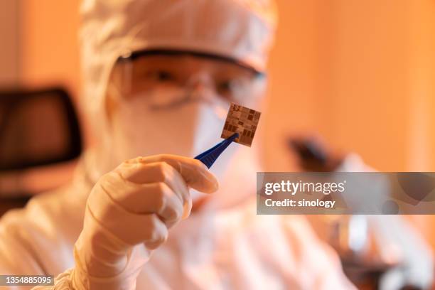 female engineer inspecting wafer chip in dust-free laboratory - halfgeleider stockfoto's en -beelden