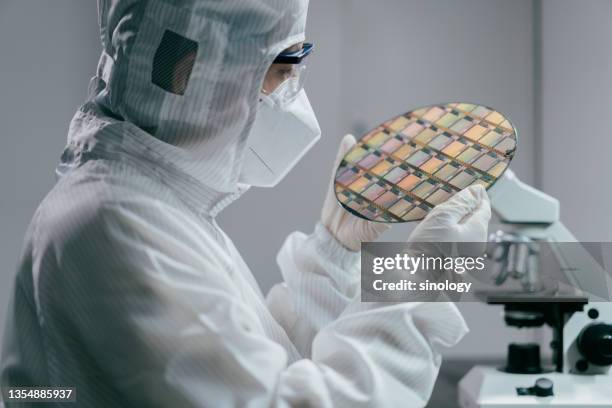 female engineer inspecting wafer chip in laboratory - cleanroom stock-fotos und bilder