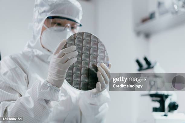 female engineer inspecting wafer chip in laboratory - semiconductor stock-fotos und bilder