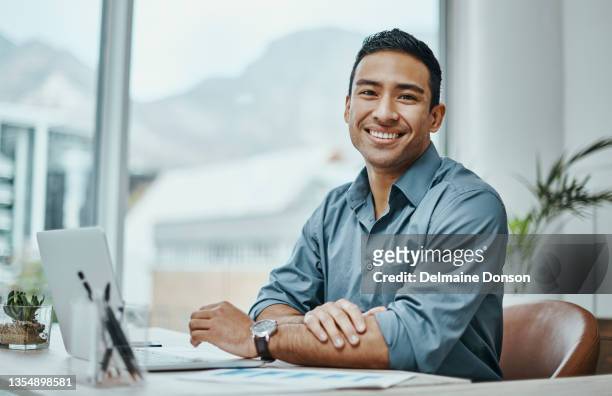 shot of a young businessman using a laptop in a modern office - professional occupation stockfoto's en -beelden