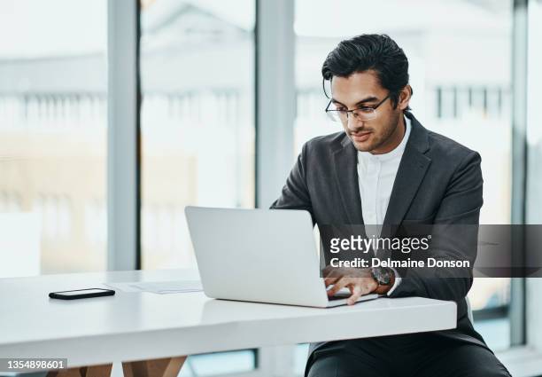 shot of a young businessman using a laptop in a modern office - using laptop stock pictures, royalty-free photos & images