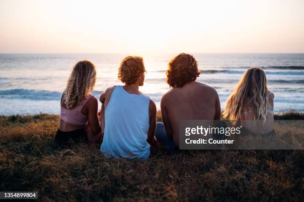 group of friends watching sun set over ocean - hossegor photos et images de collection