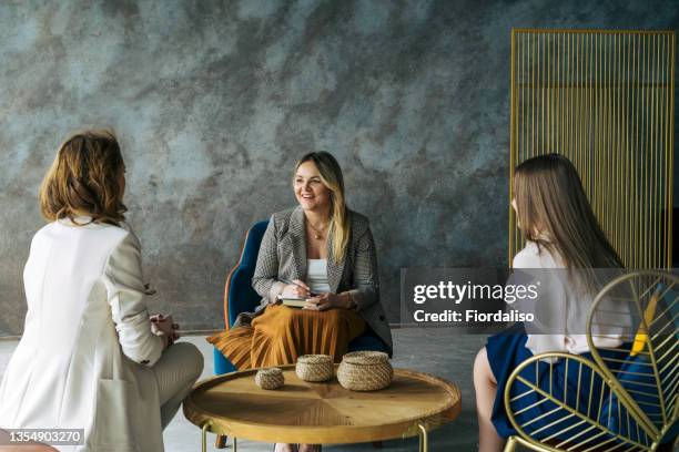 three business women talking in the office - three people sitting stock pictures, royalty-free photos & images