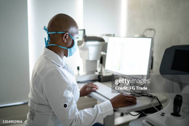 ophthalmologist analyzing exam's results in a monitor - using a face mask - retinal scan stock pictures, royalty-free photos & images