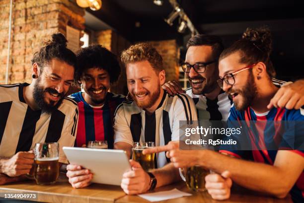 group of friends watching the football game at the pub - sport tablet stockfoto's en -beelden
