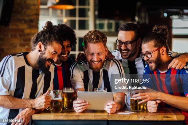 group of friends watching the football game at the pub - sport tablet stockfoto's en -beelden