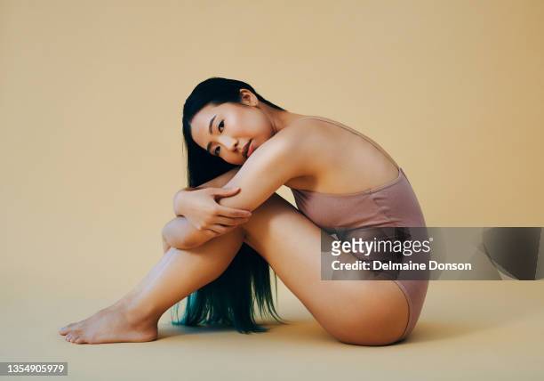 scatto a figura intera di una giovane donna attraente seduta da sola e in posa in studio - body foto e immagini stock