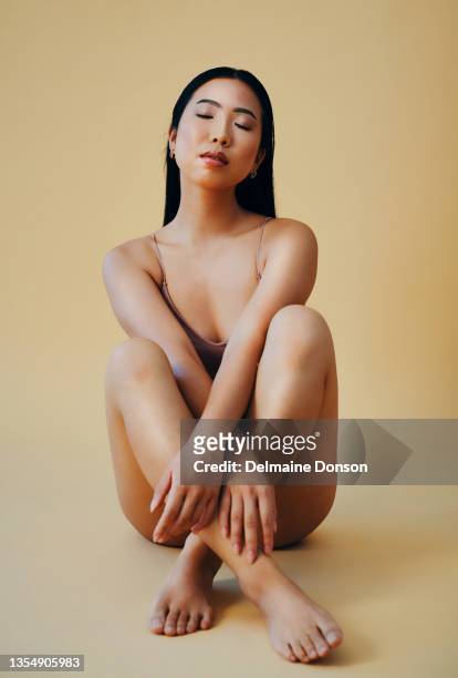 full length shot of an attractive young woman sitting alone and posing in the studio - beauty portrait studio shot stockfoto's en -beelden
