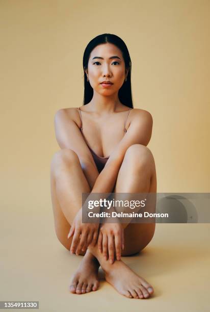 full length shot of an attractive young woman sitting alone and posing in the studio - gympak stockfoto's en -beelden