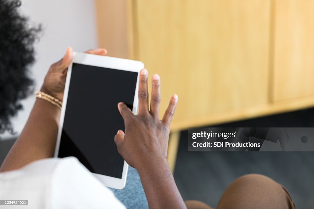 Over the shoulder view woman scrolling on tablet