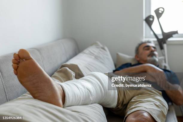 man's leg uses crutches to walk after surgery - man crutches stock pictures, royalty-free photos & images