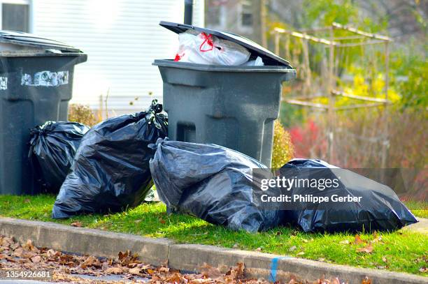 plastic garbage bags and trash can on curb - müllsack stock-fotos und bilder