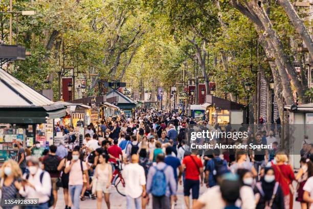 crowds of tourists walking on la rambla street in barcelona, spain - grande gruppo di persone foto e immagini stock