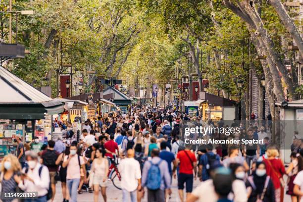 crowds of tourists walking on la rambla street in barcelona, spain - traffic free stockfoto's en -beelden