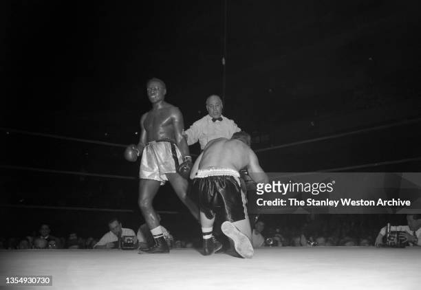 New York, NY Photo shows Ezzard Charles and Charlie Norkus on his knees with Referee Harry Kessler in the middle. Charles landed a punch on Norkus's...