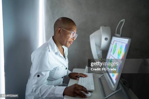 médico analizando los resultados del examen en un monitor - optometría fotografías e imágenes de stock