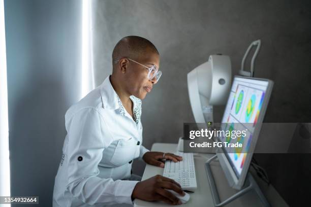 médecin analysant les résultats de l’examen dans un moniteur - ophtalmologie photos et images de collection