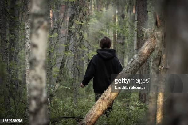 rear view of a woman in black clothes walking into forest - thick girls stockfoto's en -beelden