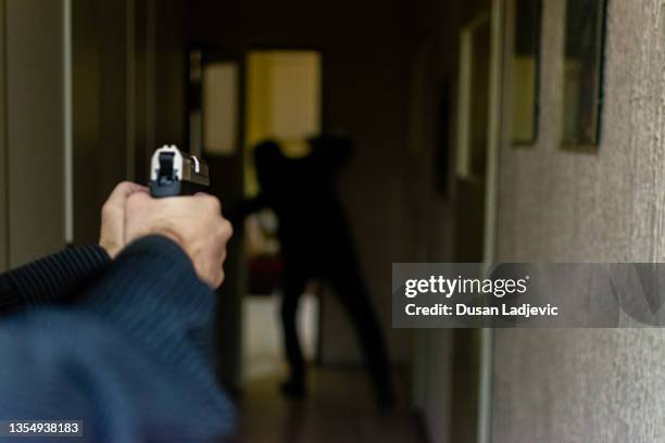 HD stock photographyof a action portrait of serious young detective, special agent, holding gun pointing the weapon, involved in shooting, entering in the the hallway in some bulding with caution, looking for and arresting a criminal.
