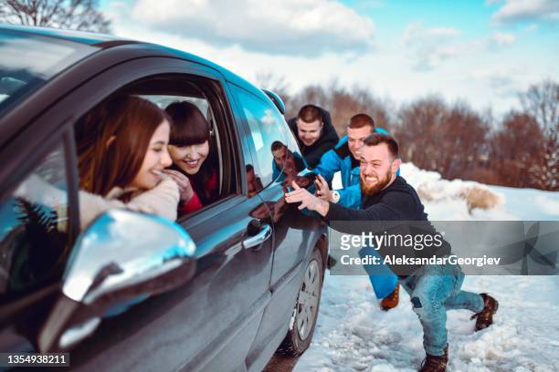 machos tentando tirar o carro da neve da montanha empurrando enquanto as fêmeas dirigem - doing a favor - fotografias e filmes do acervo