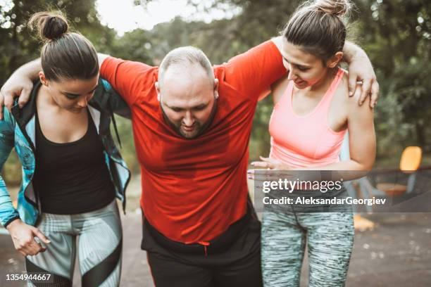 overweight male getting help from female friends after athletic activities outside - fat man lying down stock pictures, royalty-free photos & images