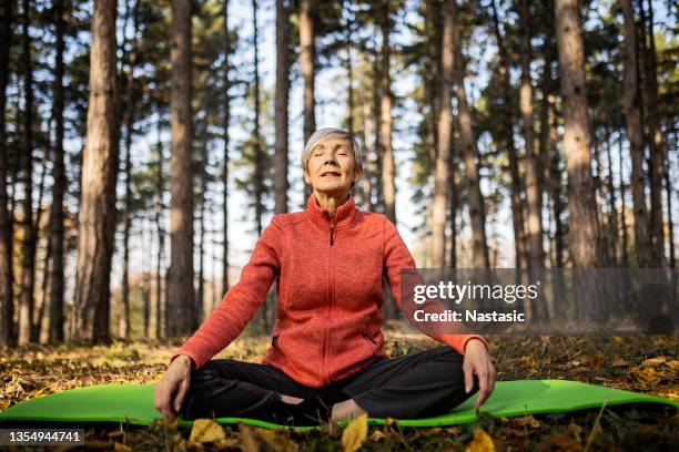 senior woman practicing yoga eyes closed - cobra stock pictures, royalty-free photos & images