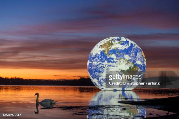 The sun sets behind artist Luke Jerram's 'Floating Earth' at Pennington Flash on November 22, 2021 in Wigan, England. The floating Earth will hover...