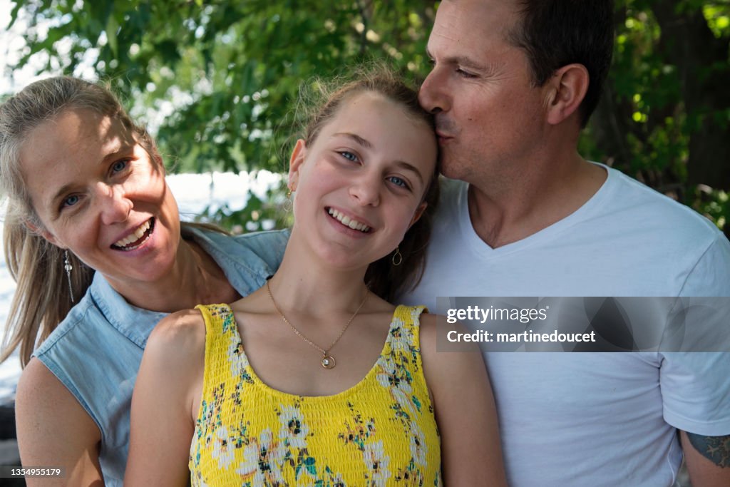 Véritable portrait de famille de parents avec une fille adolescente au bord de la rivière en été.